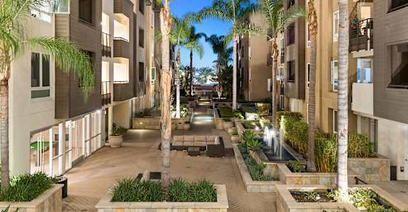 A courtyard with palm trees and a fountain in the middle.