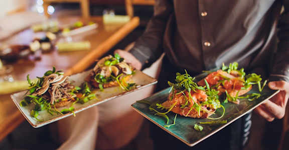 A person holding two plates with food on them.