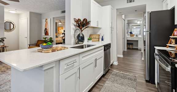 A modern kitchen with white cabinets and a black refrigerator.