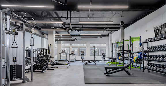 A gym with a variety of equipment including weights and weight machines.