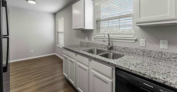 A kitchen with granite countertops and white cabinets.
