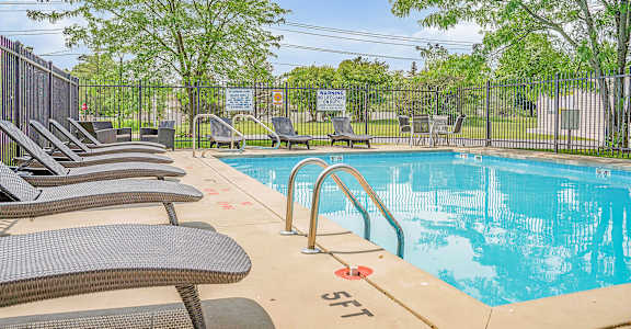 a swimming pool with chaise lounge chairs and trees in the background