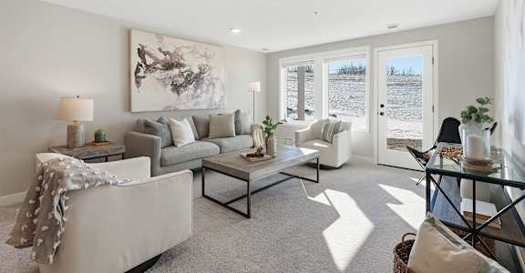 A living room with a grey couch, a glass coffee table, and a large abstract painting on the wall.