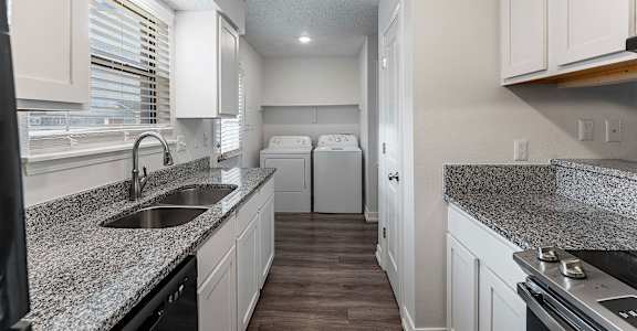 A kitchen with granite countertops and white cabinets.