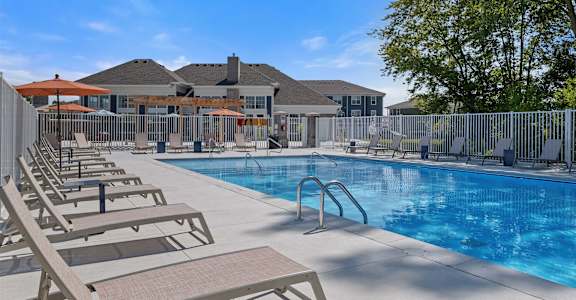 A pool with sun loungers and a building in the background.