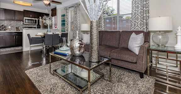 A modern living room with a glass coffee table and a brown couch.