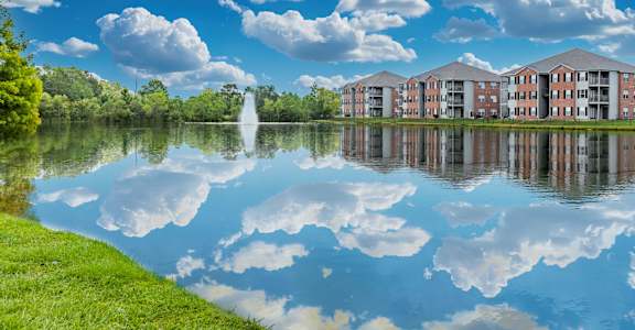 A serene lake with a building in the background and clouds in the sky.