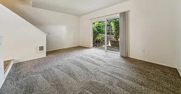 A room with a carpeted floor and a door leading outside.