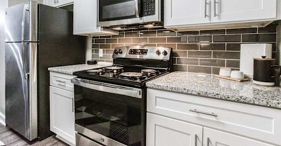 A kitchen with a black stove top oven and a black microwave above it.
