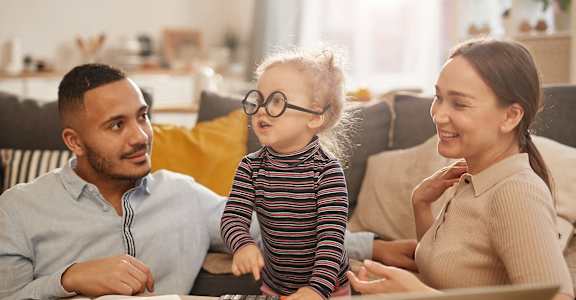 a little girl looking at a laptop computer with her parents
