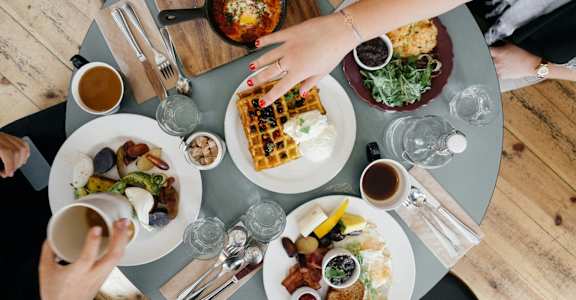 a table with plates of food on it and people sitting around it