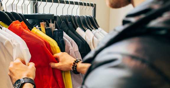 a man selecting clothes on a rack in a closet