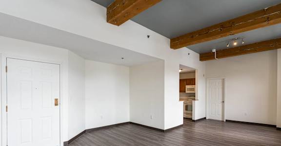 A room with a white door and wooden beams on the ceiling.
