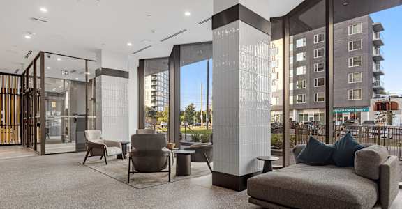 A modern living room with a grey sofa and a glass door.