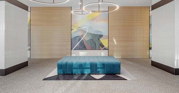 A modern room with a blue bench and a painting on the wall.