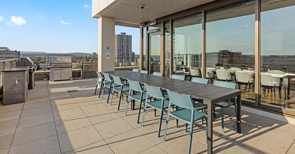 A patio with a table and chairs overlooking a cityscape.