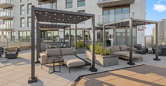 A modern outdoor seating area with a pergola and planters.