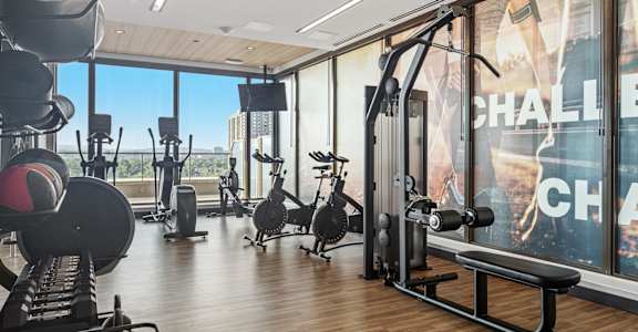 A gym with a variety of equipment including weights and a rowing machine.