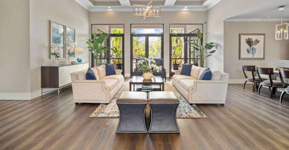 A modern living room with a large window and a wooden floor at The Grand Reserve at Tampa Palms Apartments, Tampa
