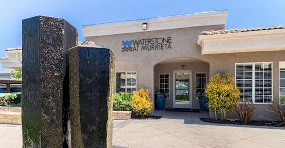 a building with a fountain in front of leasing office at waterson at murrieta