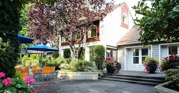 the patio and yard of a white house with a patio umbrella