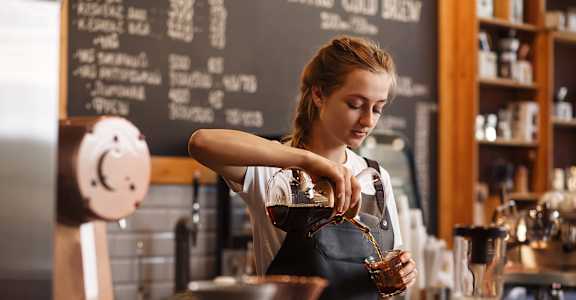 a woman pouring a cup of coffee in a coffee shop