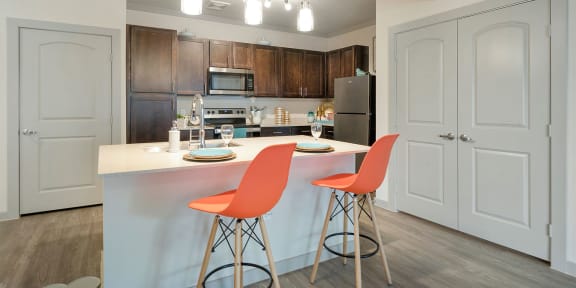 a kitchen with dark blue cabinets and two orange chairs