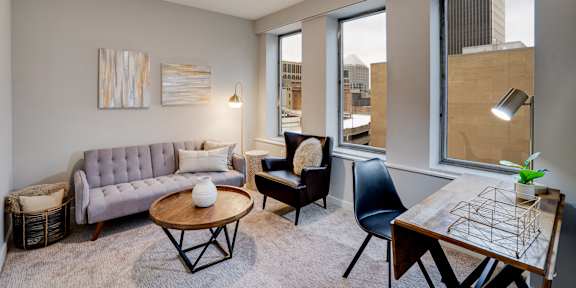 A living room with a grey couch, a coffee table, a chair, and a table with a plant on it.