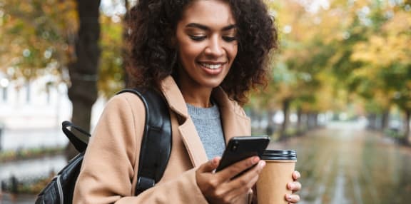 a woman looking at her phone while holding a cup of coffee  at Ashby at Ross Bridge, Hoover, 35226