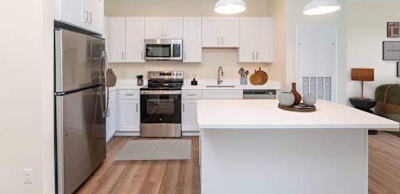 A modern kitchen with white cabinets and a stainless steel refrigerator.