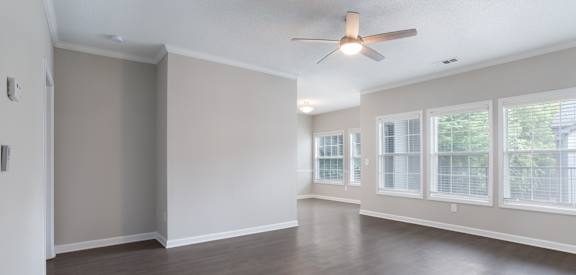 Empty room with a ceiling fan and large windows.