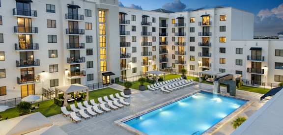 an aerial view of an apartment building with a pool and chairs District West Gables West Miami, FL