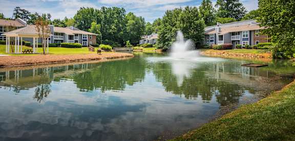 a pond with a fountain in front of houses at Arbor Ridge, Greensboro