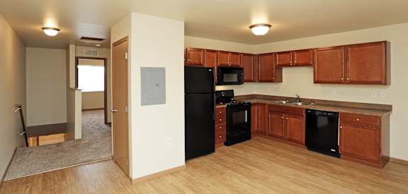a kitchen with black appliances and wood flooring