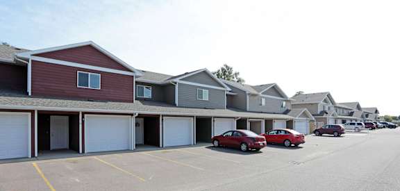 a row of houses with garages and cars in a parking lot