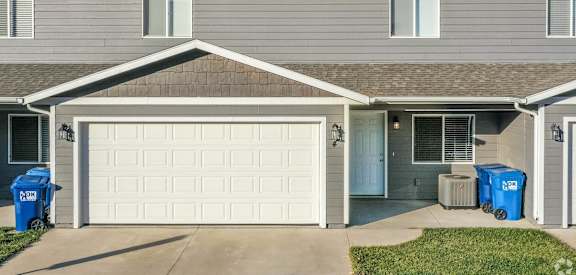 a house with a white garage door and trash cans in front of it