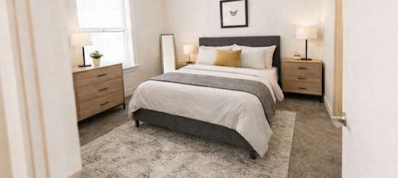A bedroom with a large bed, two nightstands, and a window.