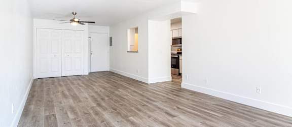 an empty living room with wood flooring and a ceiling fan
