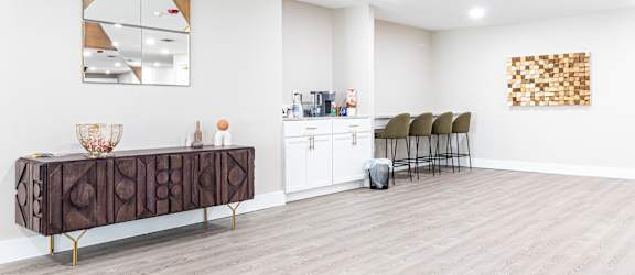 a living room with a reception desk and a bar with chairs