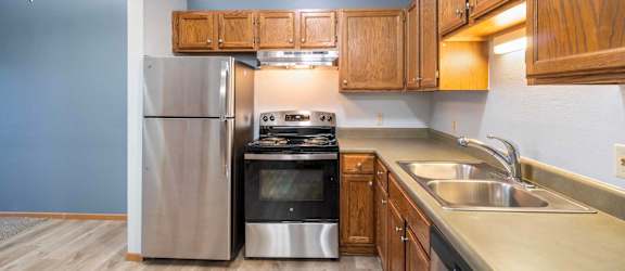 A kitchen with a stainless steel refrigerator, oven, and sink.