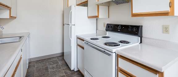 A kitchen with white appliances and wooden cabinets.