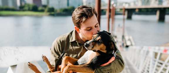 Man Holding Pet Dog while Walking