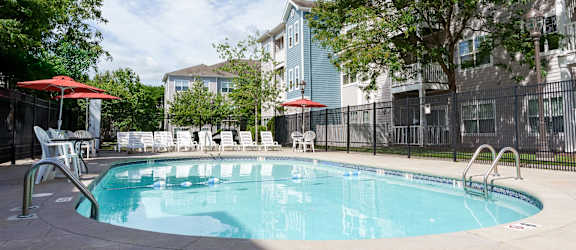 A swimming pool surrounded by chairs and umbrellas.