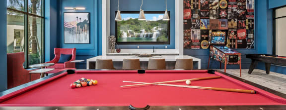 A pool table is in the middle of a room with blue walls. at Altis Twin Lakes Apartments, Kissimmee, FL 34744
