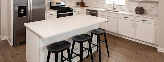 a large white kitchen with stainless steel appliances and a white counter top