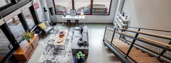 A living room with a black and white rug, a wooden coffee table, and a staircase.