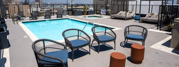 the pool at the top of a building with chairs and a swimming pool
