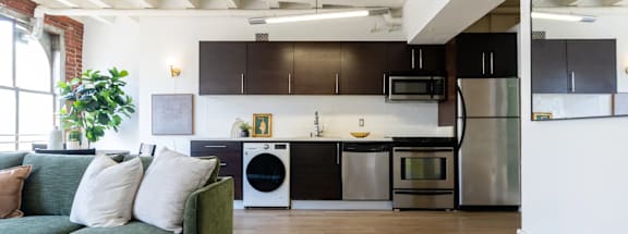a living room with a couch and a kitchen with stainless steel appliances