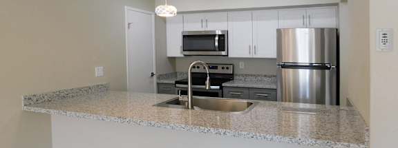 A kitchen with a granite countertop and stainless steel appliances.