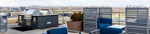 A patio with blue chairs and a table with a view of the city.